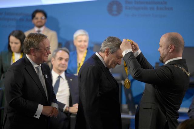 The former leader of the conservative Christian Democratic Union (CDU) party Armin Laschet (L) looks on as the former President of the European Central Bank (ECB) and former Italian Prime Minister Mario Draghi (C) is awarded with the 2026 International Charlemagne Prize of Aachen by Aachen's mayor Michael Ziemons (R) and on May 14, 2026 in Aachen, western Germany. (Photo by Sascha Schuermann / AFP)