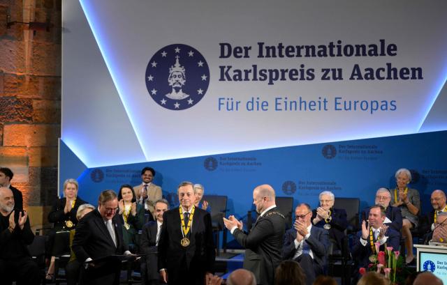 The former President of the European Central Bank (ECB) and former Italian Prime Minister Mario Draghi (C) is applauded by the former leader of the conservative Christian Democratic Union (CDU) party Armin Laschet (C-L), Aachen's mayor Michael Ziemons (C-R) and guests after he was awarded the 2026 International Charlemagne Prize of Aachen, on May 14, 2026 in Aachen, western Germany. (Photo by Sascha Schuermann / AFP)