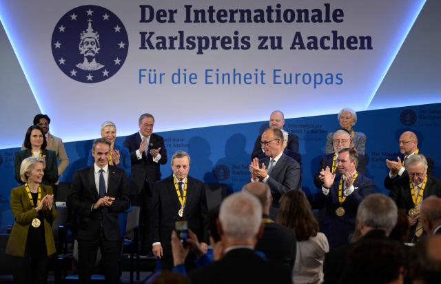 The former President of the European Central Bank (ECB) and former Italian Prime Minister Mario Draghi (C) is applauded by the President of the European Commission Ursula von der Leyen (L), Greek Prime Minister Kyriakos Mitsotakis (2nd L), German Chancellor Friedrich Merz (C-R) and other guests as he is awarded the 2026 International Charlemagne Prize of Aachen, on May 14, 2026 in Aachen, western Germany. (Photo by Sascha Schuermann / AFP)