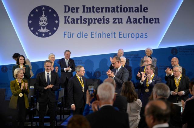 The former President of the European Central Bank (ECB) and former Italian Prime Minister Mario Draghi (C) is applauded by the President of the European Commission Ursula von der Leyen (L), Greek Prime Minister Kyriakos Mitsotakis (2nd L), German Chancellor Friedrich Merz (C-R) and other guests as he is awarded the 2026 International Charlemagne Prize of Aachen, on May 14, 2026 in Aachen, western Germany. (Photo by Sascha Schuermann / AFP)