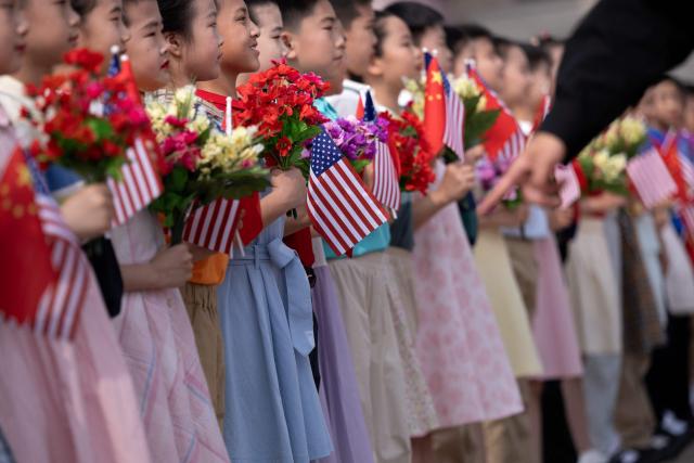 Children rehearse with flowers and flags for a welcome ceremony for US President Donald Trump at the Great Hall of the People in Beijing on May 14, 2026. (Photo by Brendan Smialowski / AFP)