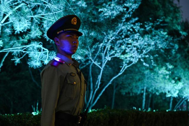 A Chinese paramilitary police officer stands guard on a street before the motorcade of US President Donald Trump passes by in Beijing on May 14, 2026. (Photo by HECTOR RETAMAL / AFP)
