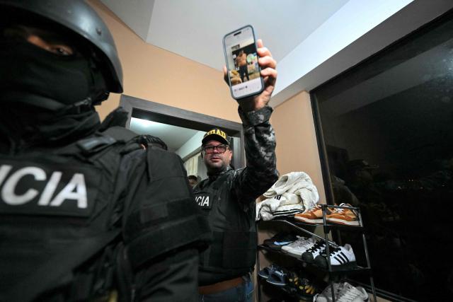 Ecuador's Interior Minister John Reimberg shows a photo of Eduardo Gomez, alias "Gordo Paul", on his mobile phone during his arrest in a police operation carried out during a curfew imposed by President Daniel Noboa to tackle organized crime, in Quito in the early hours of May 14, 2026. Ecuador's police on May 14 captured a "dangerous" leader of Los Lobos, the country's largest drug trafficking group, in a cinematic operation led by Interior Minister Jhon Reimberg, AFP reporters witnessed. (Photo by Rodrigo BUENDIA / AFP)