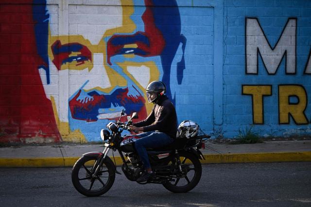 A motorcyclist rides past a mural of ousted Venezuela's President Nicolas Maduro, in Caracas, on May 14, 2026. (Photo by Federico PARRA / AFP)