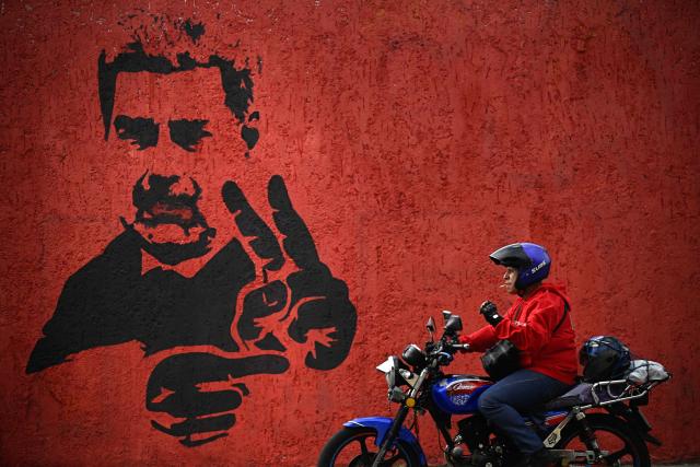 A motorcyclist rides past a mural of ousted Venezuela's President Nicolas Maduro flashing the V sign, in Caracas, on May 14, 2026. (Photo by Federico PARRA / AFP)