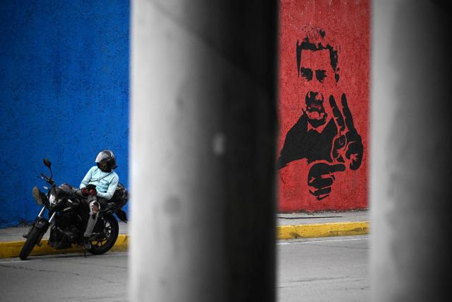 A motorcyclist rests next to a mural of ousted Venezuela's President Nicolas Maduro flashing the V sign, in Caracas, on May 14, 2026. (Photo by Federico PARRA / AFP)