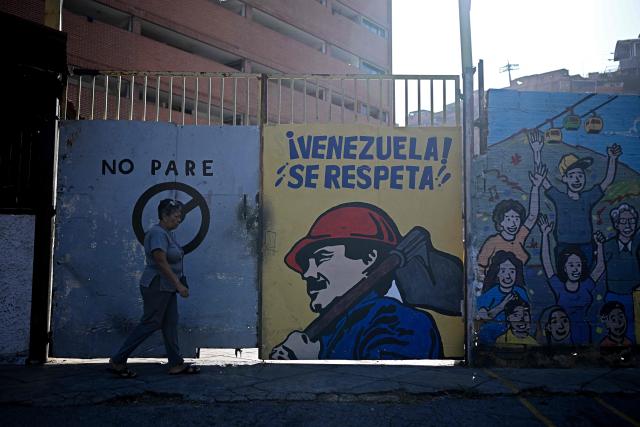A woman walks past a mural depicting ousted Venezuelan President Nicolas Maduro reading “Venezuela deserves respect!,” in Caracas on May 14, 2026. (Photo by Federico PARRA / AFP)