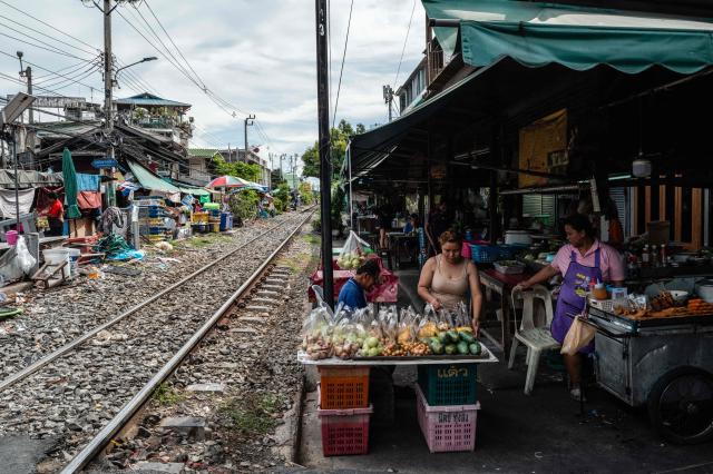 Food vendors wait for customers next to the train tracks at Wongwian Yai Railway Station in Bangkok on May 14, 2026. (Photo by ANTHONY WALLACE / AFP)