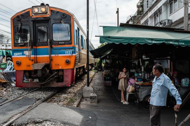 A man waits near food vendor stalls as a SRT (State Railway of Thailand) train pulls into Wongwian Yai Railway Station in Bangkok on May 14, 2026. (Photo by ANTHONY WALLACE / AFP)