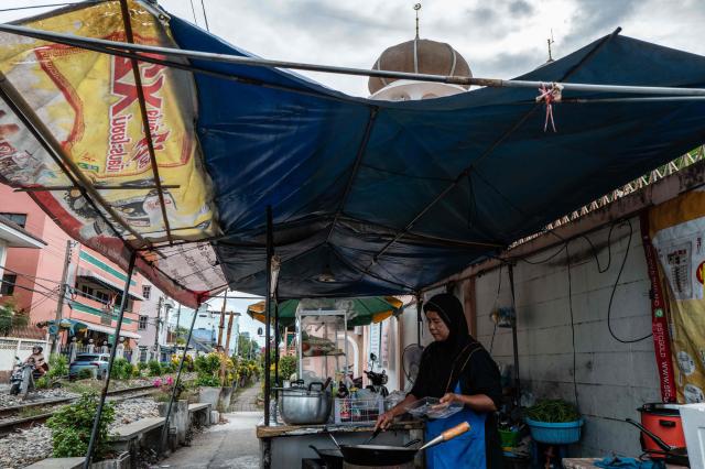 A Muslim woman cooks at her food stall along train tracks outside Suan Phlu Mosque (top) in Bangkok on May 14, 2026. (Photo by ANTHONY WALLACE / AFP)