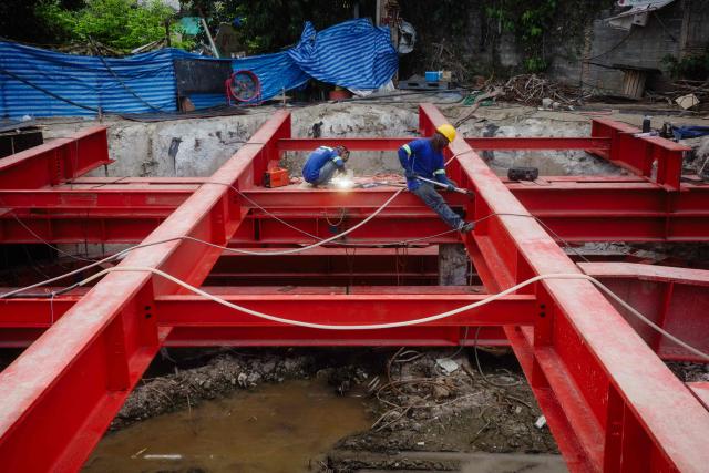 Construction workers sit on shoring beams at a building site in Bangkok on May 14, 2026. (Photo by ANTHONY WALLACE / AFP)