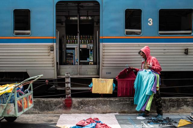 A worker collects items of clothing before placing them onto a cart on the side of train tracks at Wongwian Yai Railway Station in Bangkok on May 14, 2026. (Photo by ANTHONY WALLACE / AFP)