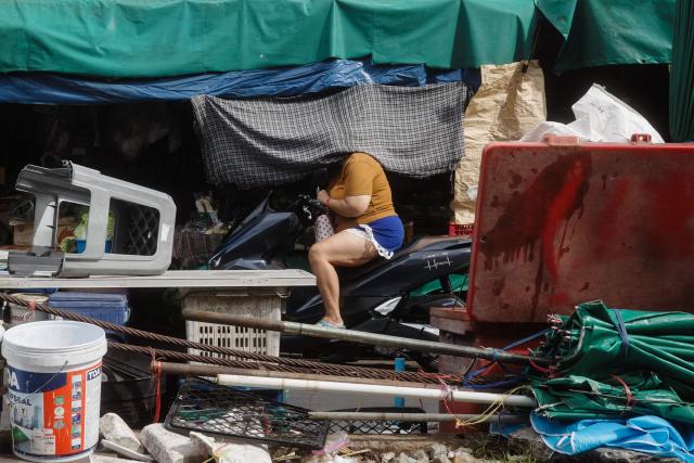 A motorist buys goods from a street vendor next to train tracks at Wongwian Yai Railway Station in Bangkok on May 14, 2026. (Photo by ANTHONY WALLACE / AFP)