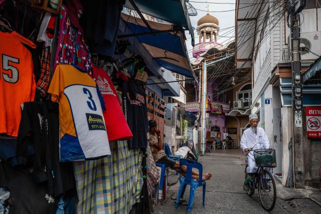 A Muslim man rides his bicycle past a cloth vendor near Suan Phlu Mosque (back C) in Bangkok on May 14, 2026. (Photo by ANTHONY WALLACE / AFP)