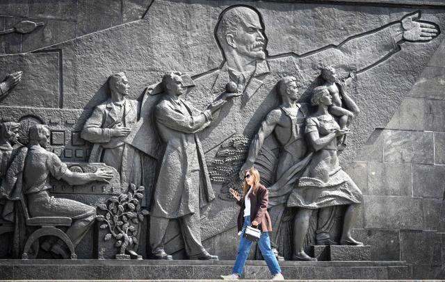 A woman walks in front of a Soviet era bas-relief depicting Vladimir Lenin showing the way to the Soviet people in VDNKh park in Moscow on May 14, 2026. (Photo by Alexander NEMENOV / AFP)