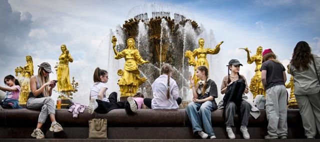People have fun by the "Friendship of Nations" fountain at the All-Russia Exhibition Centre (VDNKh) in Moscow on May 14, 2026. The fountain was installed at the All-Russia Exhibition Centre (VDNKh), a trade show and amusement park, in 1954, with 16 gilded bronze sculptures of young women representing 16 republics of the USSR around the oval fountain bowl featuring a wheat sheaf. (Photo by Alexander NEMENOV / AFP)