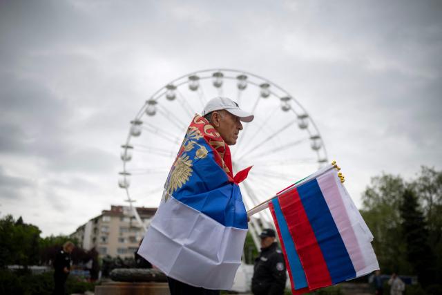 (FILES) A man holds a Russian flag in front of the dismentled Soviet Army monument during a celebration of the Victory Day marking the anniversary of the victory over Nazi Germany during World War II, in Sofia on May 9, 2026. Bulgaria's Rumen Radev won April's election with backing from traditional pro-Russian voters, but festivities commemorating the end of World War II showed he has not charmed all in the EU member historically close to Russia. (Photo by Nikolay DOYCHINOV / AFP)
