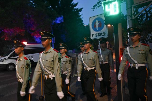 Chinese paramilitary police officers patrol before the motorcade of US President Donald Trump passes by in Beijing on May 14, 2026. (Photo by Pedro PARDO / AFP)