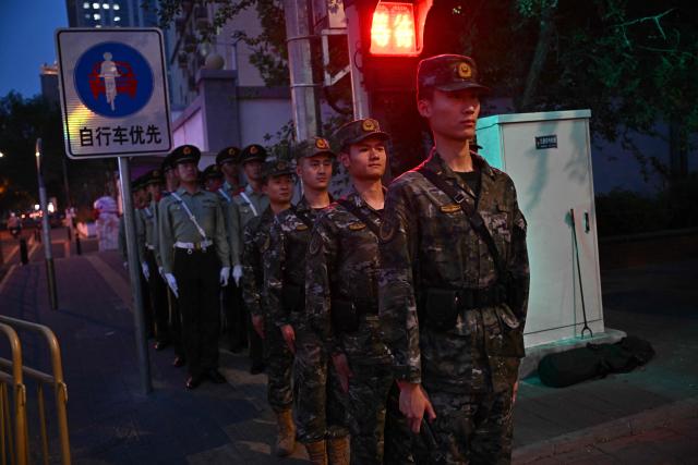 Chinese paramilitary police officers patrol before the motorcade of US President Donald Trump passes by in Beijing on May 14, 2026. (Photo by Pedro PARDO / AFP)