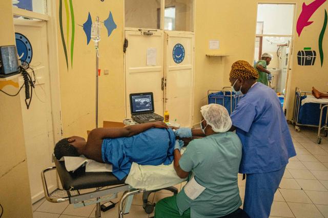 A surgeon working with the International Committee of the Red Cross (ICRC) examines a gunshot-wounded patient using a sonar device to locate a fragment lodged in the patient’s leg, at a hospital in Goma on May 14, 2026. (Photo by Jospin Mwisha / AFP)