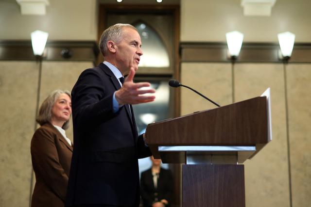 Canadian Prime Minister Mark Carney, alongside Minister of the Environment, Climate Change and Nature Julie Aviva Dabrusin (L), speaks during a news conference on Parliament Hill in Ottawa, Canada, on May 14, 2026. Carney announced a new agenda on clean energy initiatives. (Photo by Dave Chan / AFP)