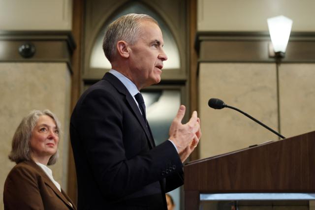 Canadian Prime Minister Mark Carney, alongside Minister of the Environment, Climate Change and Nature Julie Aviva Dabrusin (L), speaks during a news conference on Parliament Hill in Ottawa, Canada, on May 14, 2026. Carney announced a new agenda on clean energy initiatives. (Photo by Dave Chan / AFP)