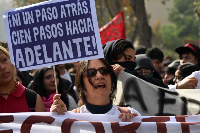 A woman holding a sign reading "Not a step back, one hundred steps forward!" as she shouts slogans during a highschool and University students protest against the government of Chile's President Jose Antonio Kast in Santiago on May 14, 2026. (Photo by RODRIGO ARANGUA / AFP)