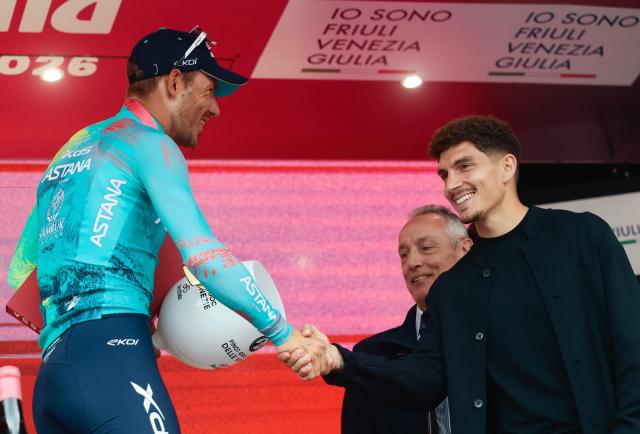 XDS Astana Team Italian rider Davide Ballerini (L) shakes hands on the podium with Napoli's Italian defender Giovanni Di Lorenzo after winning the 6th stage of the Giro d'Italia 2026 - Tour of Italy cycling race between Paestum and Naples, southern Italy on May 14, 2026. (Photo by Luca Bettini / AFP)