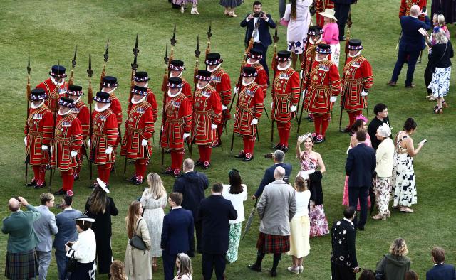 Guests take photographs of members of the The Kings's Body Guard of the Yeomen of the Guard during a Royal Garden Party at Buckingham Palace, in London, on May 14, 2026, to celebrating the 50th Anniversary of the King’s Trust. (Photo by Henry NICHOLLS / POOL / AFP)