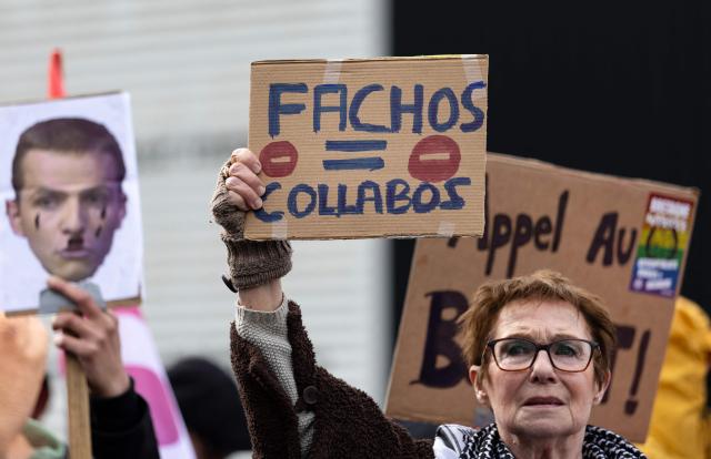 A woman holds a placard reading "fascists = collaborators" during a protest against the opening of a brewery by journalist and far-right activist Erik Tegner in Pleguien, western France on May 14, 2026. Tegner, a commentator on CNews television and co-founder of the far-right outlet Frontières, opened the Kerfave craft brewery alongside a business partner in the Cotes-d'Armor department, with anti-fascist groups mobilising against the launch. (Photo by Fred TANNEAU / AFP)