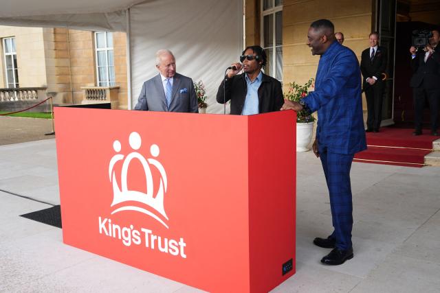 Britain's King Charles III reacts as he talks with DJ Christian St Louis and actor Idris Elba during a Royal Garden Party at Buckingham Palace, in London, on May 14, 2026, celebrating the 50th Anniversary of the King’s Trust. (Photo by Aaron Chown / POOL / AFP)