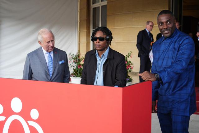 Britain's King Charles III reacts as he talks with DJ Christian St Louis and actor Idris Elba during a Royal Garden Party at Buckingham Palace, in London, on May 14, 2026, celebrating the 50th Anniversary of the King’s Trust. (Photo by Aaron Chown / POOL / AFP)