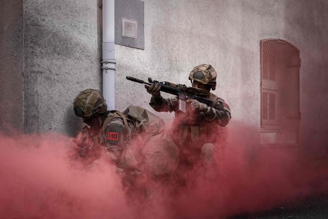 French Foreign Legion paratroopers from the 2nd Foreign Parachute Regiment (2e REP) advance through a smoke-filled alley during a urban assault exercise in La Souterraine, central France, on May 14, 2026. The exercise, running from May 11 to 20 across Nouvelle-Aquitaine and Centre-Val de Loire, tests short-notice redeployment and interoperability between air and ground components — capabilities central to France's contribution to NATO rapid-reaction forces. (Photo by Philippe LOPEZ / AFP)