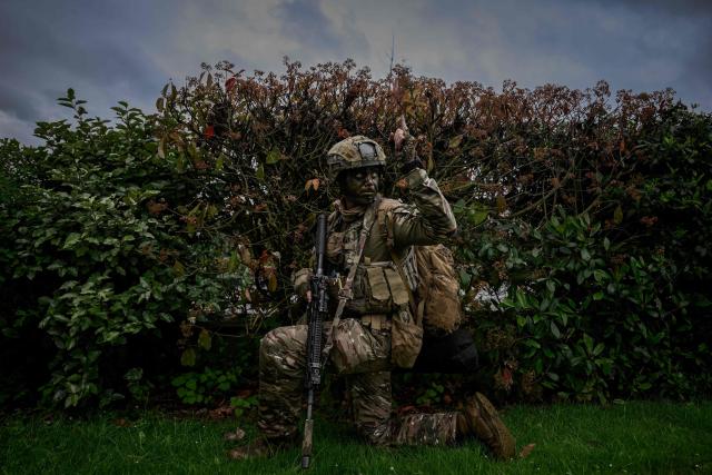 A French Foreign Legion paratrooper from the 2nd Foreign Parachute Regiment (2e REP) signals to his unit while taking cover behind a hedge during a urban assault exercise in La Souterraine, central France, on May 14, 2026. The exercise, running from May 11 to 20 across Nouvelle-Aquitaine and Centre-Val de Loire, tests short-notice redeployment and interoperability between air and ground components — capabilities central to France's contribution to NATO rapid-reaction forces. (Photo by Philippe LOPEZ / AFP)