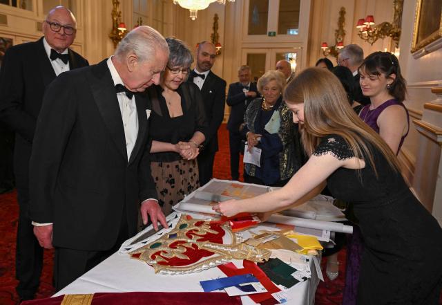 Britain's King Charles III is shown by Anne Butcher, Head of Studio and Standards at the Royal School of Needlework (R) a display of items used to create the new stage curtains ahead of 'Spring Gala: Stories from The Royal Ballet and The Royal Opera' at the Royal Opera House in London on May 14, 2026. (Photo by Jeff Spicer / POOL / AFP)