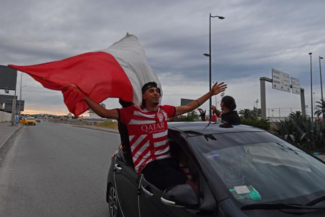 Fan holds a flag in a vehicle while celebrating the victory title of the Club Africain football team in the 2025/2026 Tunisian Ligue 1 championship, in Tunis on May 14, 2026. (Photo by FETHI BELAID / AFP)