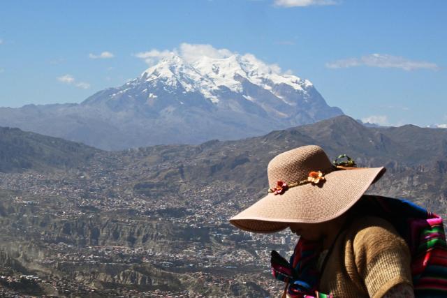 An indigenous woman walks past with the snow-capped Illimani mountain on the background in La Paz on May 14, 2026. (Photo by Aizar RALDES / AFP)