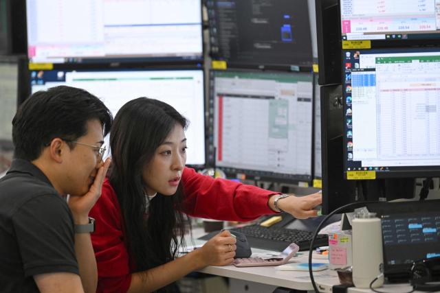 Currency dealers monitor exchange rates in a foreign exchange dealing room at the Hana Bank headquarters in Seoul on May 15, 2026. South Korea's benchmark Kospi index topped 8,000 points for the first time on May 15, buoyed by an artificial intelligence-driven boom in the country's semiconductor industry. (Photo by Jung Yeon-je / AFP)