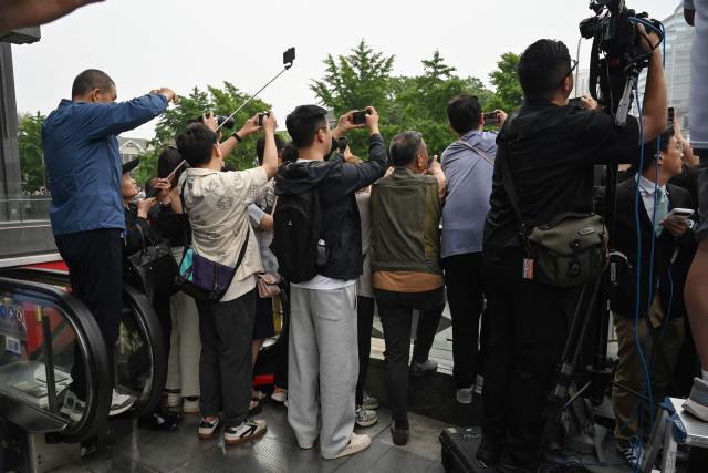 People take photos as US President Donald Trump’' motorcade departs a hotel on the way to a meeting with China’s President Xi Jinping in Beijing on May 15, 2026. (Photo by GREG BAKER / AFP)