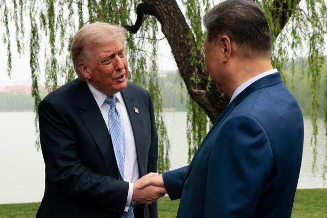 US President Donald Trump (L) is greeted by Chinese President Xi Jinping at Zhongnanhai Garden in Beijing on May 15, 2026. (Photo by Evan Vucci / POOL / AFP)