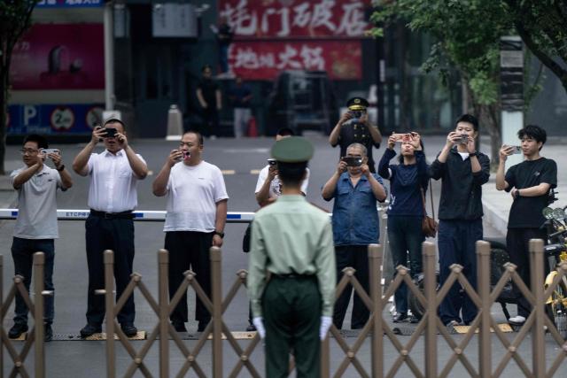 People watch the motorcade of US President Donald Trump as it travels to the Zhongnanhai leadership compound for a meeting with China’s President Xi Jinping in Beijing on May 15, 2026. (Photo by Brendan Smialowski / AFP)