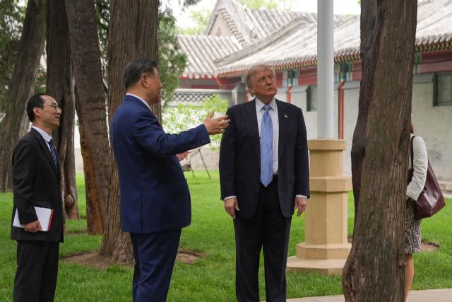 US President Donald Trump (R) talks to China’s President Xi Jinping (C) at the Zhongnanhai leadership compound in Beijing on May 15, 2026. (Photo by Mark Schiefelbein / POOL / AFP)