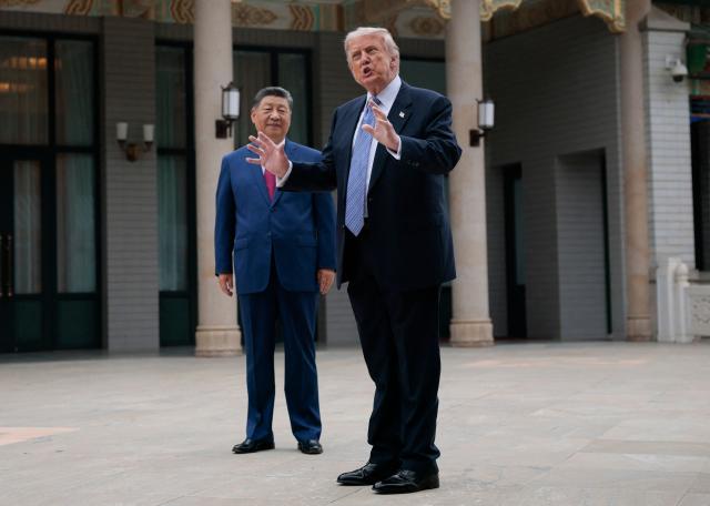 US President Donald Trump (R) gestures as he poses for photos with China’s President Xi Jinping during a visit to Zhongnanhai Garden in Beijing on May 15, 2026. (Photo by Evan Vucci / POOL / AFP)