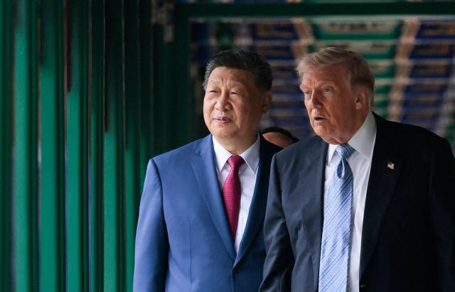 US President Donald Trump (R) walks with China’s President Xi Jinping (L) at Zhongnanhai Garden in Beijing on May 15, 2026. (Photo by Evan Vucci / POOL / AFP)