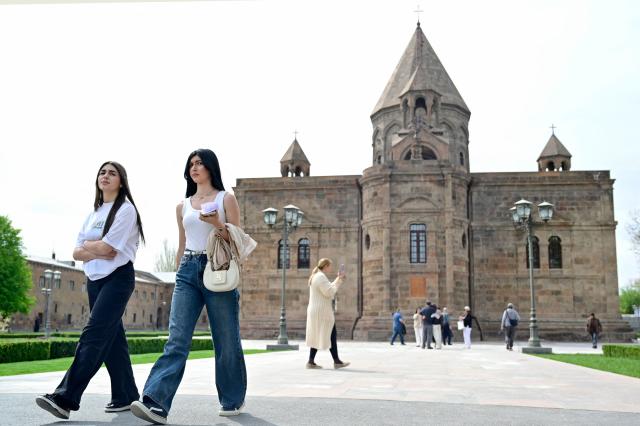 People walk outside the Etchmiadzin Cathedral in Echmiadzin, Armenia's ancient spiritual centre and the seat of the leader of the Armenian Apostolic Church, outside Yerevan, on April 18, 2026. (Photo by KAREN MINASYAN / AFP)