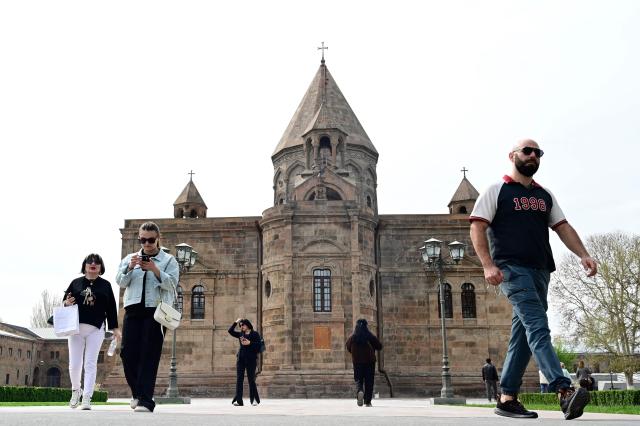 People walk outside the Etchmiadzin Cathedral in Echmiadzin, Armenia's ancient spiritual centre and the seat of the leader of the Armenian Apostolic Church, outside Yerevan, on April 18, 2026. (Photo by KAREN MINASYAN / AFP)