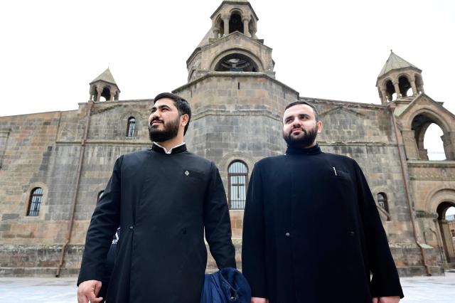 Hovhanes Avetisyan (R), a deacon from the city of Armavir with 12 years of church service, poses outside the Etchmiadzin Cathedral in Echmiadzin, Armenia's ancient spiritual centre and the seat of the leader of the Armenian Apostolic Church, outside Yerevan, on April 18, 2026. (Photo by KAREN MINASYAN / AFP)