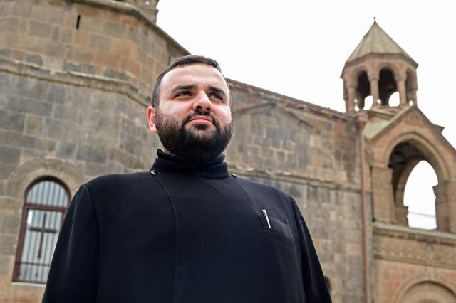 Hovhanes Avetisyan, a deacon from the city of Armavir with 12 years of church service, poses outside the Etchmiadzin Cathedral in Echmiadzin, Armenia's ancient spiritual centre and the seat of the leader of the Armenian Apostolic Church, outside Yerevan, on April 18, 2026. (Photo by KAREN MINASYAN / AFP)