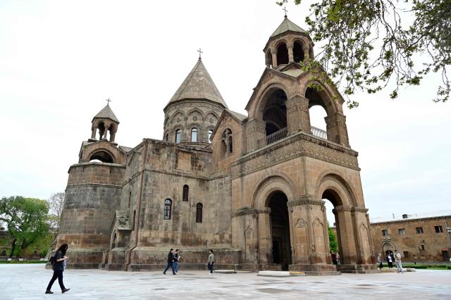 People walk past the Etchmiadzin Cathedral in Echmiadzin, Armenia's ancient spiritual centre and the seat of the leader of the Armenian Apostolic Church, outside Yerevan, on April 18, 2026. (Photo by KAREN MINASYAN / AFP)