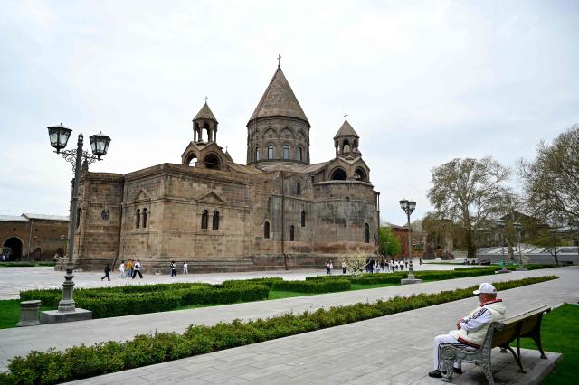 A man sits on a bench near the Etchmiadzin Cathedral in Echmiadzin, Armenia's ancient spiritual centre and the seat of the leader of the Armenian Apostolic Church, outside Yerevan, on April 18, 2026. (Photo by KAREN MINASYAN / AFP)